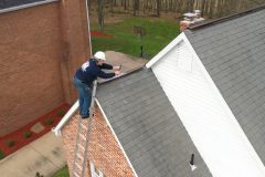 Roofing contractor on ladder assessing roof