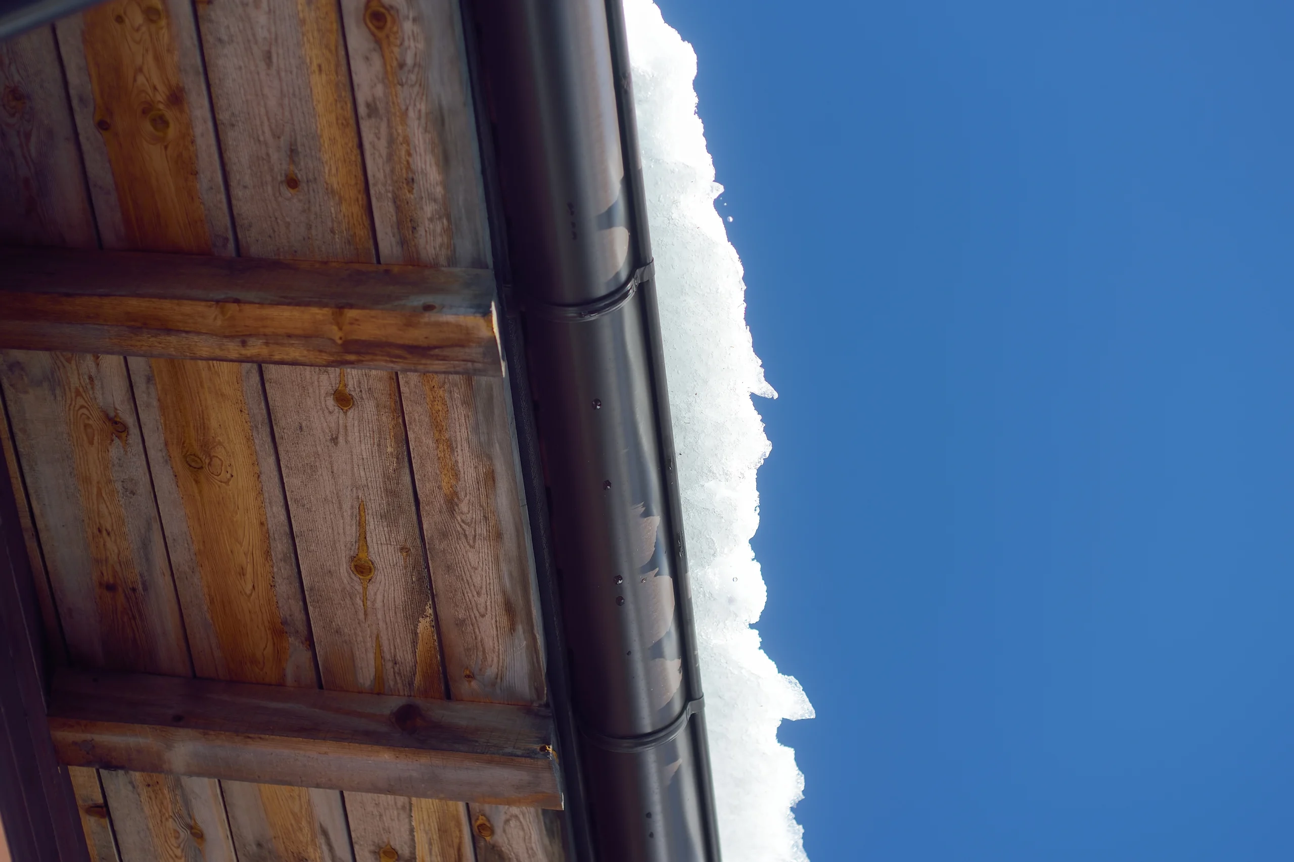snowy roof and gutters with blue sky on a winter day, How to Tell if Your Roof Has Hail Damage